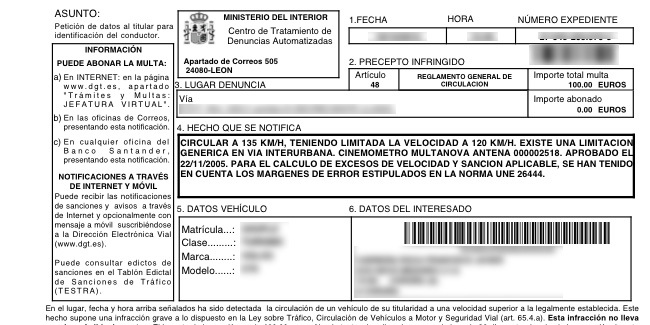 Volante y salpicadero de un coche con una multa de tráfico por exceso de velocidad y una señal de límite de velocidad al fond