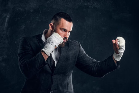 Hombre de negocios con vendas de boxeo en los puños y posición de combate