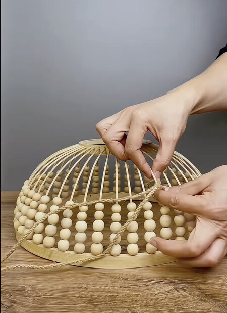 Una lámpara con cuentas de madera y cuerda.