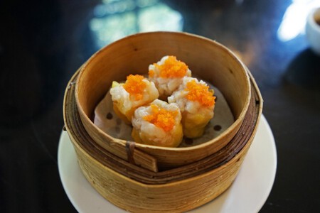 Primer plano de shumai dim sum de cerdo y gambas, dumplings chinos servidos en una cesta de bambú al vapor