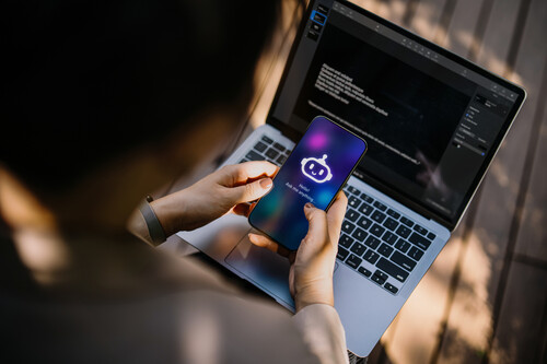 Pessoa mexendo em computador e celular. Créditos: banco de imagens
