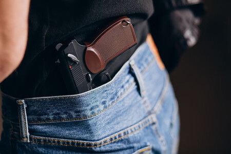 Primer plano de pistola escondida en la parte trasera de un pantalón vaquero