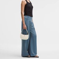 Prada parece, pero no lo es: el bolso mini de media luna perfecto para diario en la tienda que no esperas 