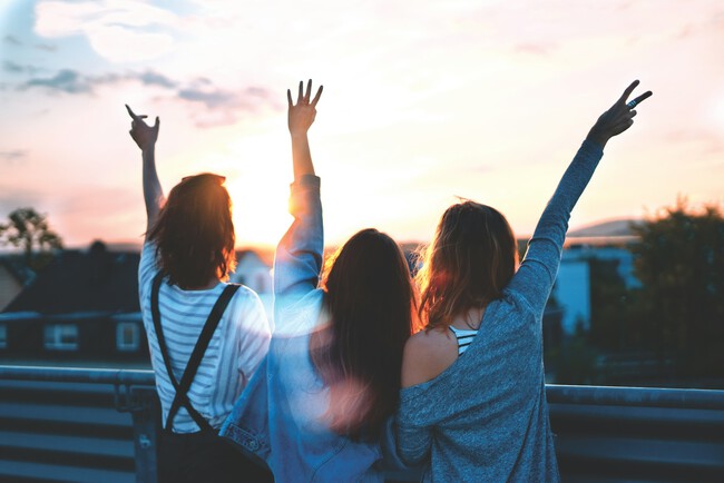 Imagen de tres chicas levantando las manos