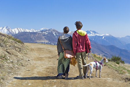 Una pareja paseando por la montaña con su perro