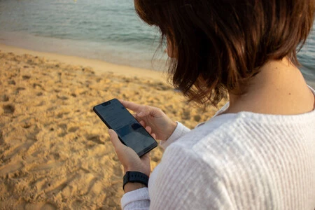 Mujer usando el móvil en una playa