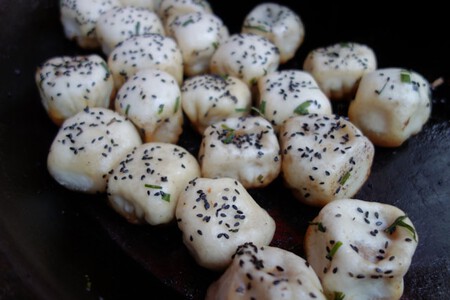 Un montón de shengjian bao en una sartén