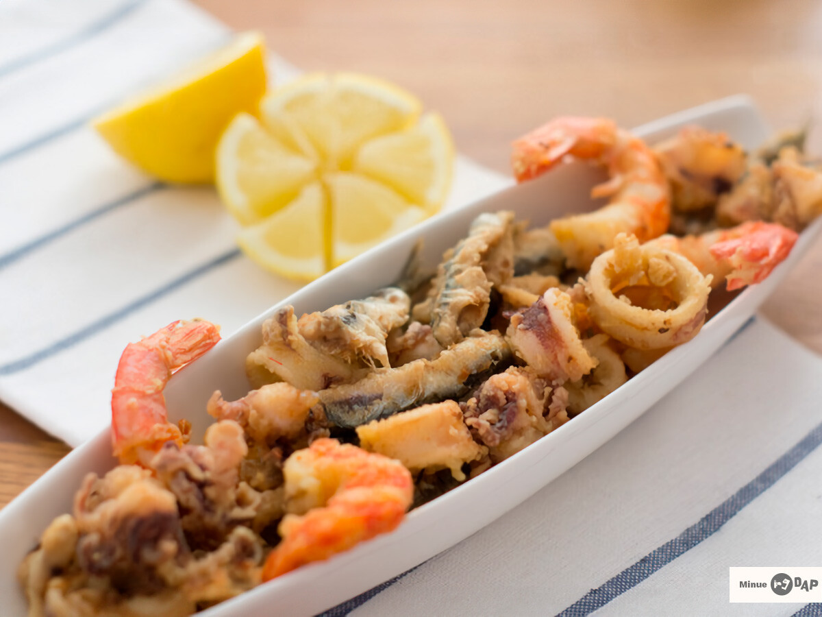 Pescado frito con rebozado crujiente dorado, servido en un plato blanco