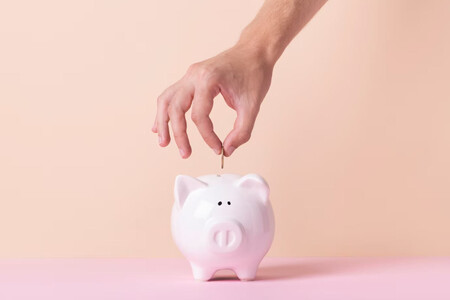 Mano metiendo moneda en hucha de cerdito. Hay algunos remedios para las decisiones irracionales que nos permitirán ahorrar más
