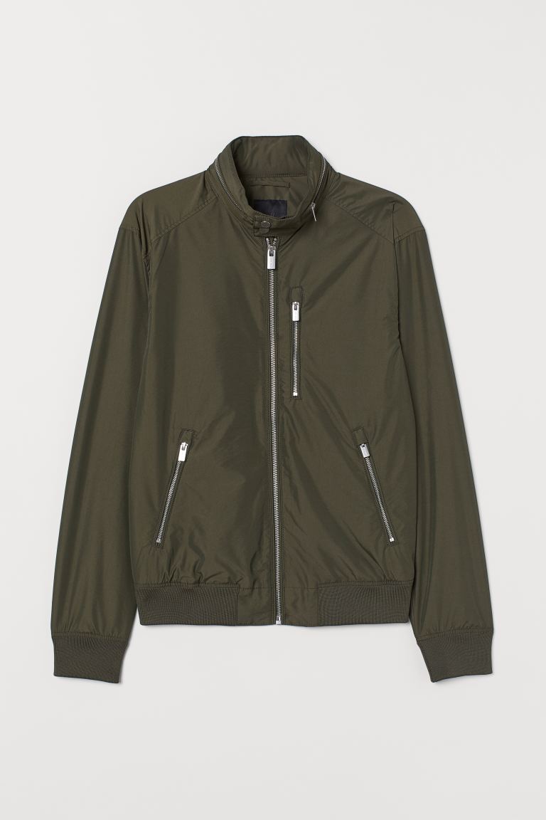 Cazadora bomber en mezcla de nailon con cuello elevado con cremallera. Capucha fina plegable que puede guardarse dentro del cuello. Modelo con cremallera delante, un bolsillo superior, bolsillos delanteros con cremallera y un bolsillo interior con botón de presión oculto. Puños y bajo en punto elástico de canalé. Forrada.