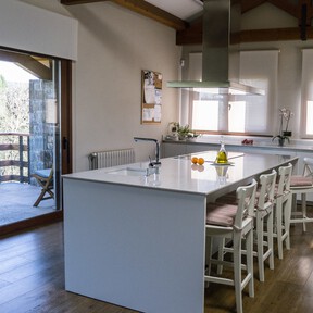 Una cocina amplia y luminosa con una espectacular isla: tiene una puerta corredera translúcida para acceder a la terraza que hace de pared acristalada