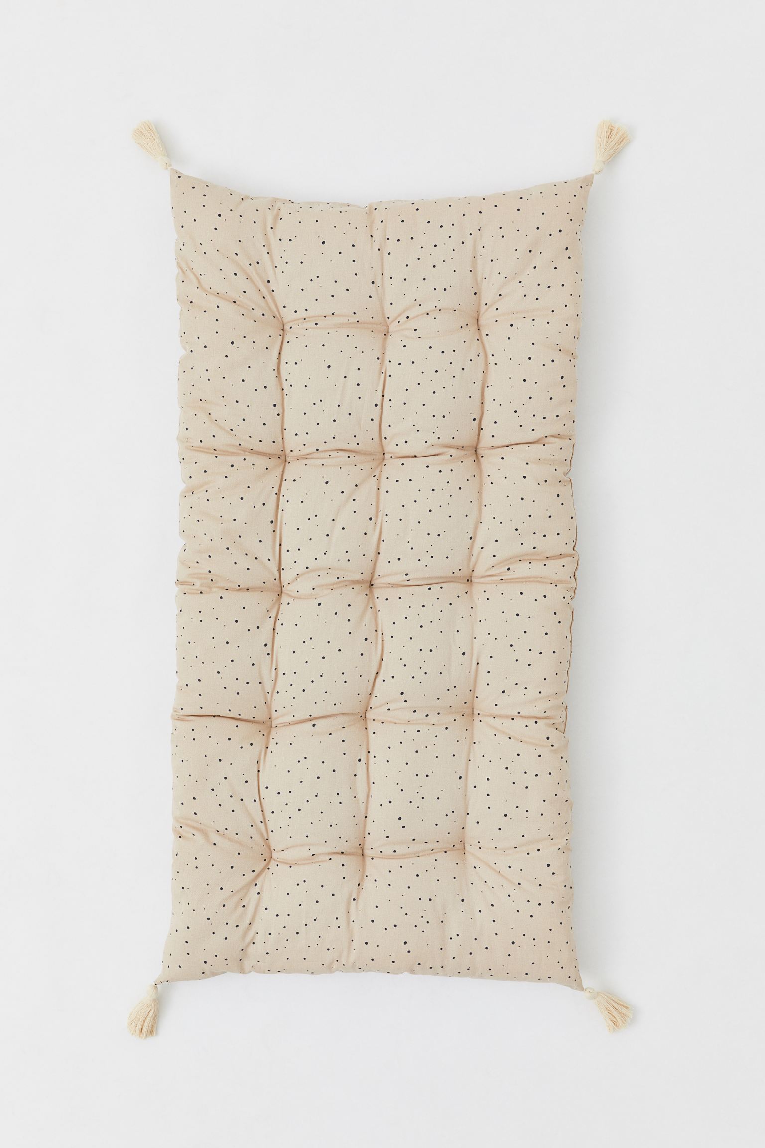 Cojín rectangular para silla en tejido de algodón con diseño estampado y una borla en cada esquina.