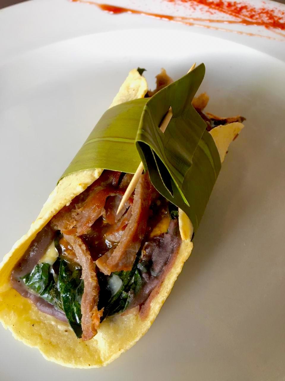 Taco de hoja santa rellena de quesos con salsa de chile meco y tasajo