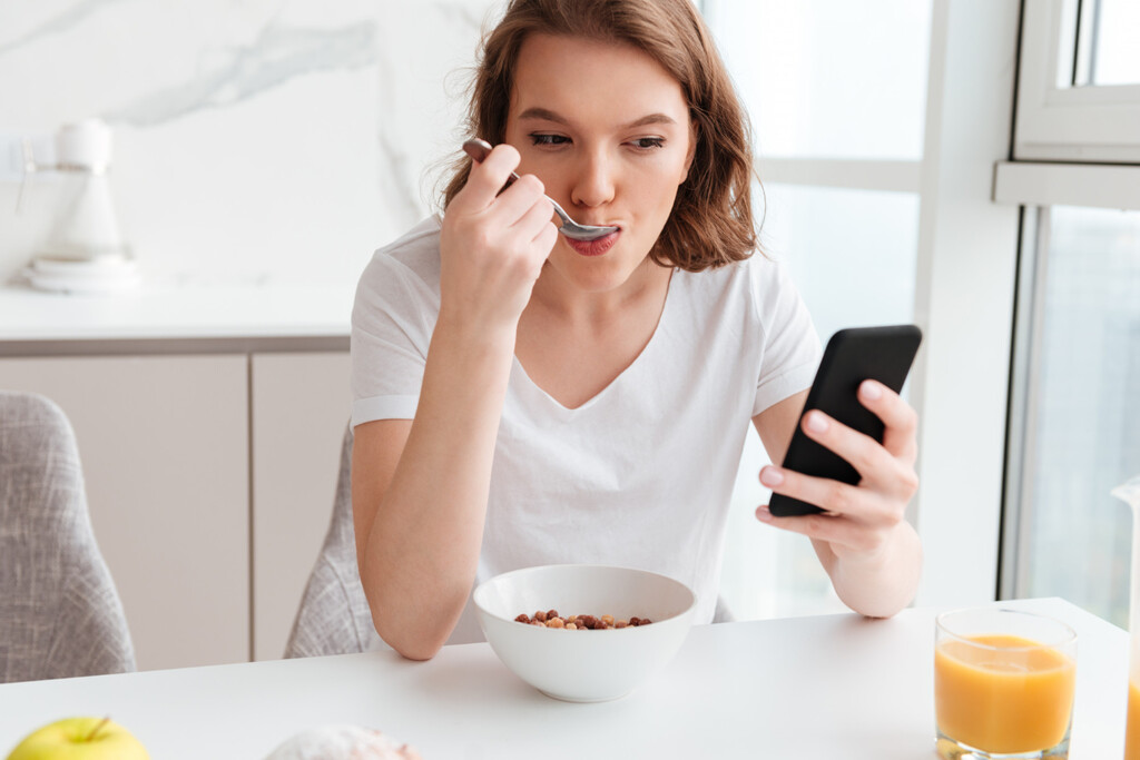 Creíamos que comer con el móvil en la mano era inofensivo. La ciencia avisa de que está "hackeando" nuestra saciedad