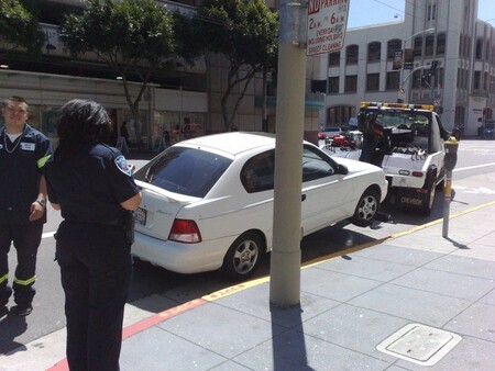 Policía local y grúa llevándose un coche