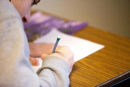 Foto de una persona escribiendo en un folio