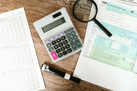 Calculadora y papeles y una lupa sobre una mesa.