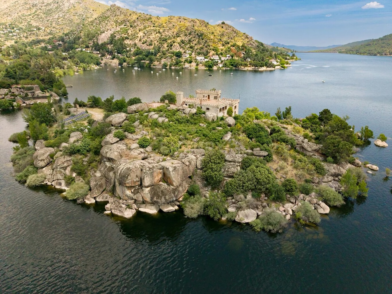 Castillo ubicado en una isla del embalse de El Burguillo, Ávila, con torres almenadas y terrazas