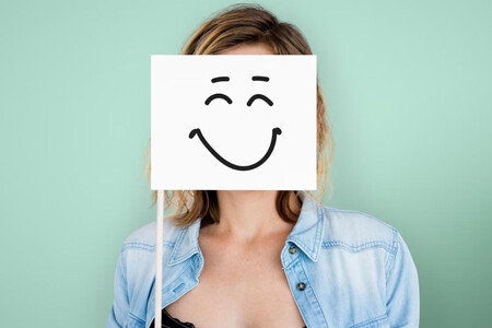 Mujer joven poniendo delante de su rostro un papel con una sonrisa dibujada