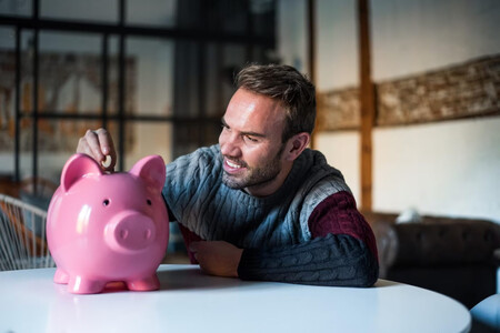 Hombre depositando una moneda en una hucha de cerdito, la disciplina es clave para ahorrar