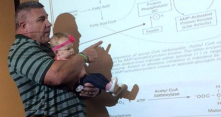 Un profesor sostiene en brazos a la bebé de una alumna que se había puesto a llorar