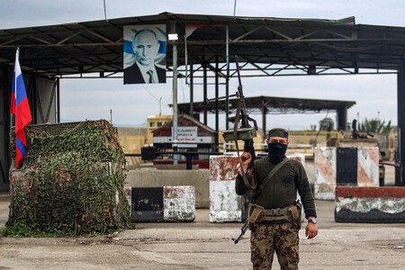 Combatente rebelde sírio em posto de inspeção de veículos, guardando entrada da base militar síria de Hmeimim, arrendada pela Rússia, na província de Latakia, em 2024