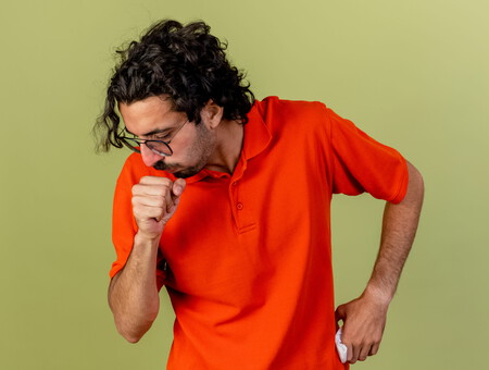 Young Ill Man Wearing Glasses Holding Napkin Keeping Hand Waist Fist Near Mouth Coughing Isolated Olive Green Wall 1