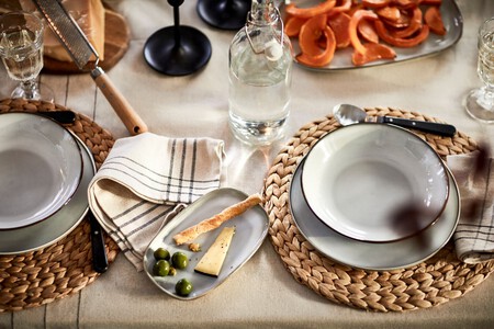 Mesa de comedor con vajilla blanca y bajoplatos
