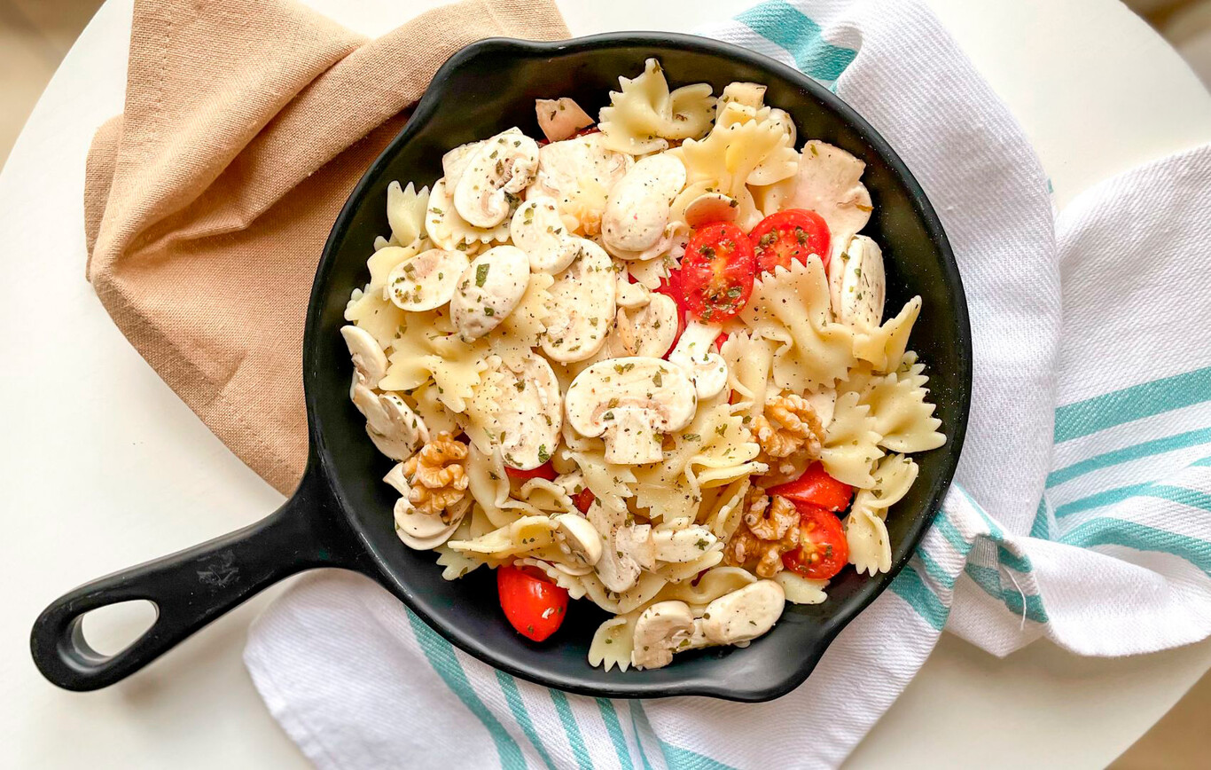 Plato de pasta templada con champiñones marinados, tomates cherry y vegetales frescos