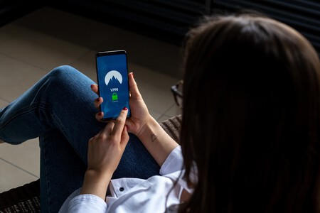 Mulher mexendo em um celular. A tela mostra uma imagem de cadeado com texto "VPN"