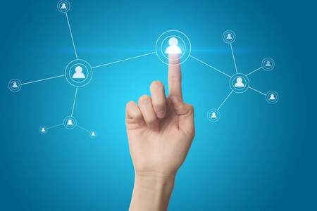 Una mano pulsando en un icono de contacto, rodeado de otros iconos similares en forma de red, dejando claro que el networking es fundamental para conseguir promociones en el trabajo