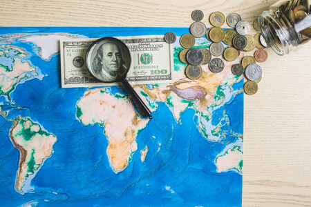 Mapa del mundo con una lupa, billetes y monedas encima