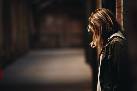 Female Leaning Against The Wall Looking Down In Hallway With Blurred Background In Alcatraz Island