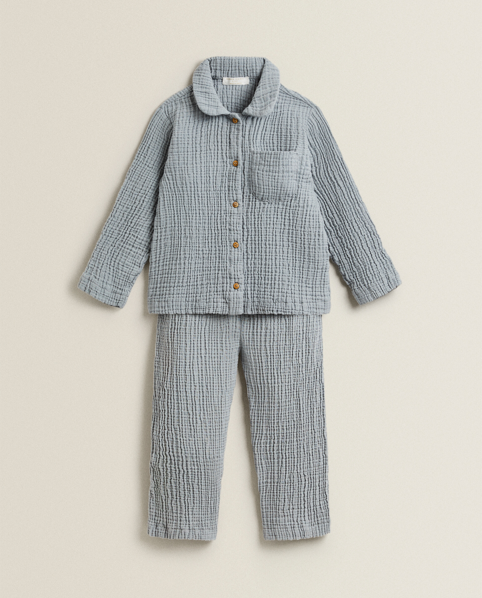 Pijama infantil de dos piezas. Confeccionado en gasa de algodón de color marrón topo. Manga y pantalón largos con detalle de cuello camisero.