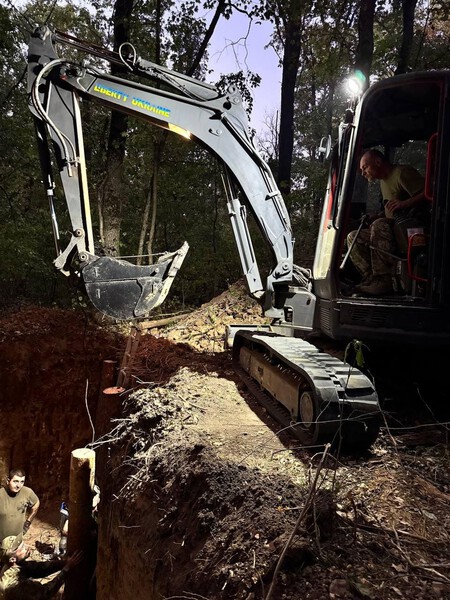 Ukrainian soldier operating an excavator near the front.