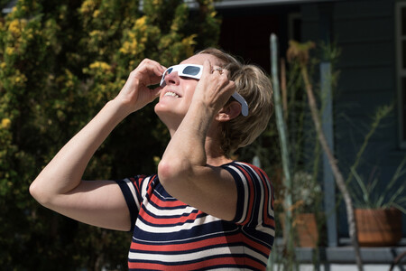 Mulher observando o céu com óculos apropriado para eclipses. Crédito: 	Spiderplay/ GettyImages