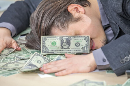 Hombre recostado sobre un montón de billetes