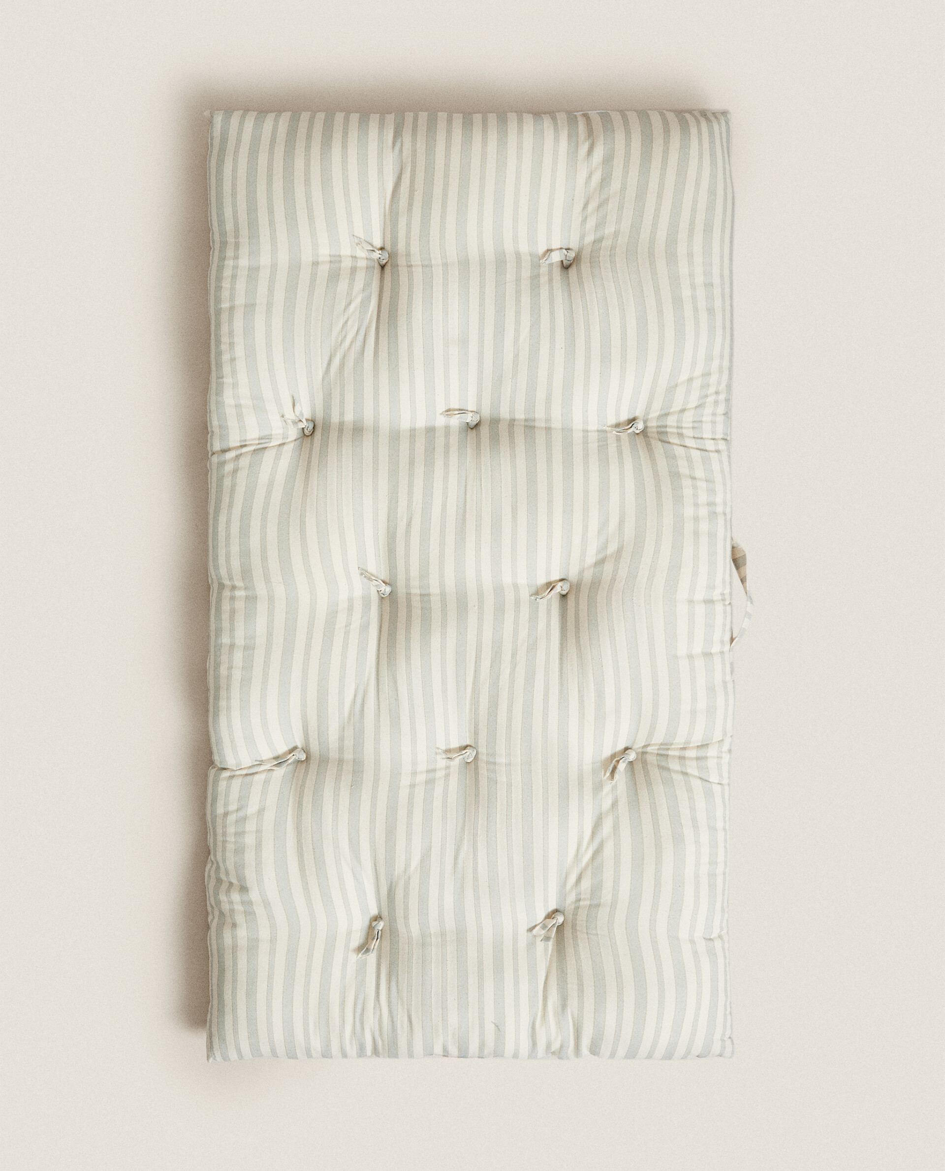 Cojín de suelo de algodón con diseño de rayas a contraste.