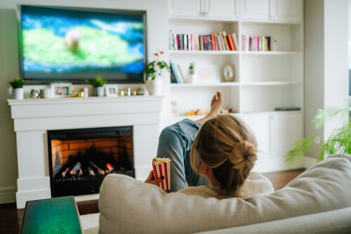 mulher sentada em sofá vendo televisão