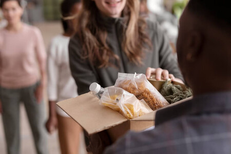 Mujer entregando una caja con alimentos como donación