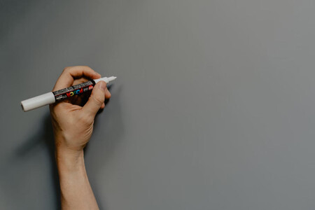 Mano Izquierda con rotulador a punto de pintar una pared gris