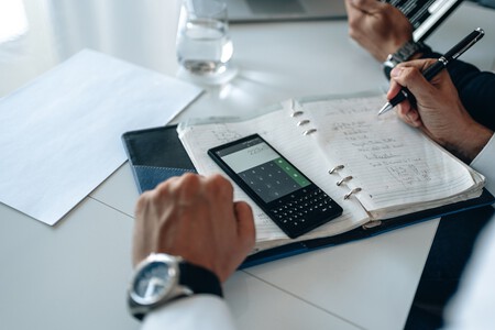 Manos de hombre con calculadora y libreta.