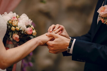 Primer plano de un novio poniendo el anillo en el dedo de su novia durante una boda