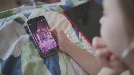 Imagem foca em uma adolescente assistindo vídeos verticais no app TikTok no celular