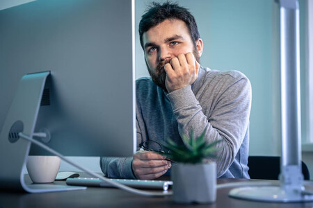 Hombre con barba mirando hastiado la pantalla de su ordenador en el trabajo