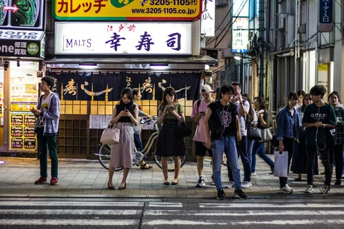 Foto de varias personas usando el móvil en un paso de cebra de Tokio (Japón)
