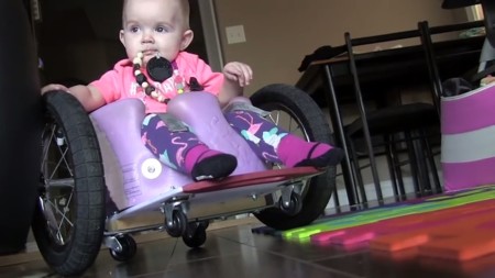 Fabricaron una silla de ruedas casera para su hija de 13 meses con parálisis (y la domina así de bien)