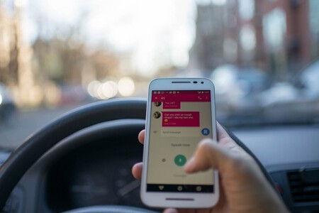 Conductor usando servicio de mensajes con el móvil en la mano