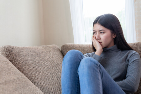 Close Up Face Of Unhappy Asian Pretty Young Woman Sitting Alone On Couch