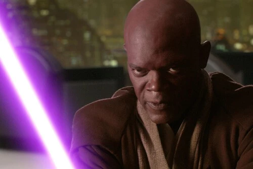 The image features a close-up of a serious-looking man with a shaved head, wearing a brown robe typical of a Jedi from the Star Wars universe. He is holding a glowing purple lightsaber, which casts light on his focused face. The background is blurred but suggests a nighttime cityscape with numerous small lights.